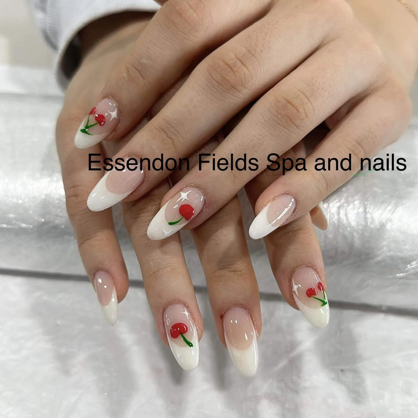 Almond nude French tips with red cherry and white star art, glossy, on silver foil