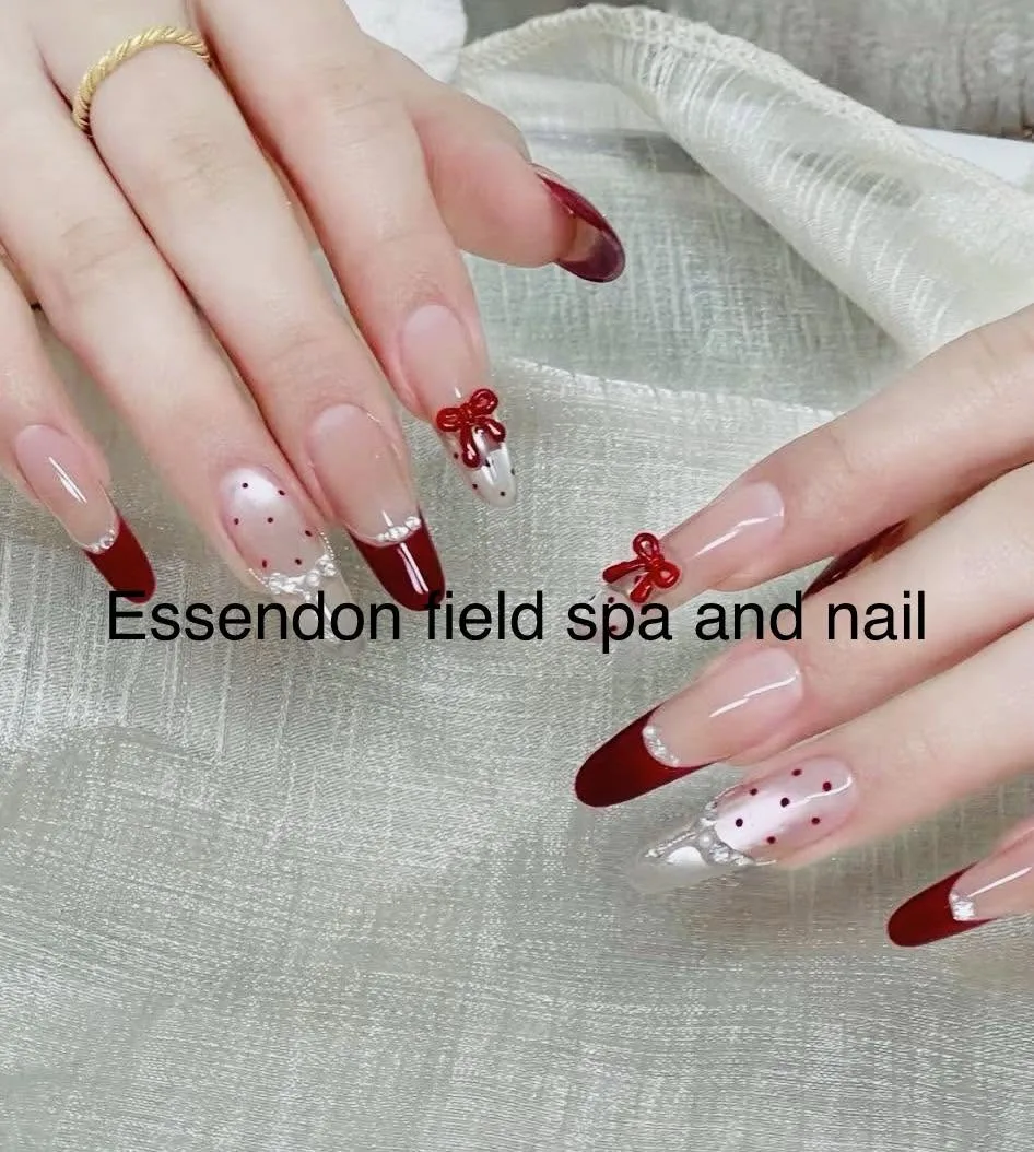 Coffin nails in deep burgundy French with 3D red bow, pearl and polka-dot accents, on champagne fabric